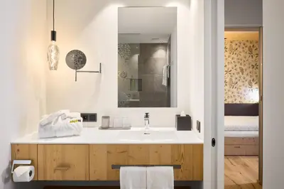 a bathroom with a white sink and a bed at Movi Family Apart-Hotel ****s in Corvara in Badia