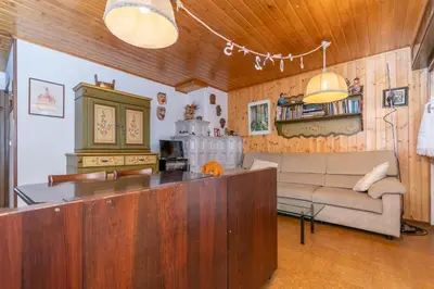 a kitchen and living room with a couch and a counter at Dimora al Vajolet in Pozza di Fassa