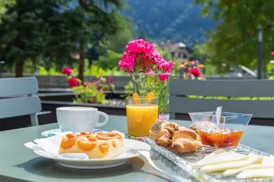 a table with a plate of pastries and a cup of orange juice at Cusanus Akademie - Accademia Cusanus in Bressanone
