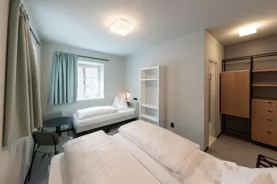 a bedroom with two beds and a desk and a table at Cusanus Akademie - Accademia Cusanus in Bressanone