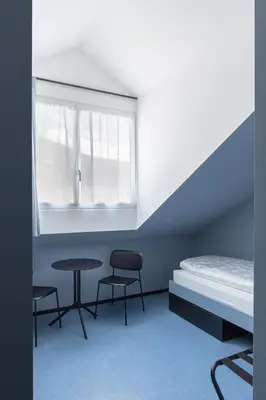 a room with a bed and two chairs and a table at Cusanus Akademie - Accademia Cusanus in Bressanone