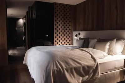 a bedroom with a large white bed with a wooden wall at Residence Chalet L'Salvan in Selva di Val Gardena
