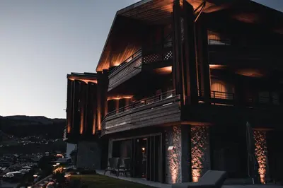 a large wooden building with a sunset in the background at Residence Chalet L'Salvan in Selva di Val Gardena