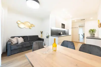 a kitchen and living room with a table and a couch at Meranosuites - Therme in Merano