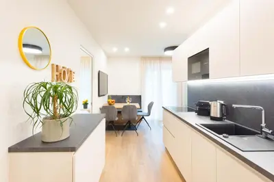 a kitchen with white cabinets and a table with a plant at Meranosuites - Therme in Merano