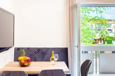 a table with a bowl of fruit and a bottle of wine at Meranosuites - Therme in Merano
