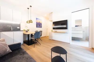 a kitchen and a living room with a table and chairs at CityPointApartments-Park in Merano
