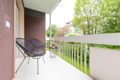 a balcony with two chairs and an umbrella at CityPointApartments-Park in Merano