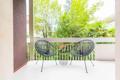 two chairs and a table on a balcony at CityPointApartments-Park in Merano