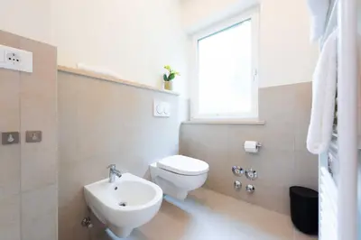 a bathroom with a toilet and a sink and a window at CityPointApartments-Park in Merano