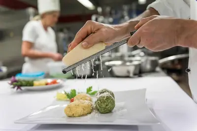 a chef is sprinkling sauce onto a plate of food at Hotel Onach in San Lorenzo di Sebato