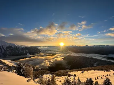 a view of a snowy mountain with the sun in the sky at Pitznerhof in Maranza