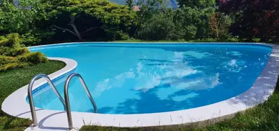 a swimming pool with blue water in a yard at Gasserhof Bozen in Bolzano
