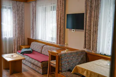 a hotel room with a couch and a tv at Appartements Residence Ganthaler in Rablà