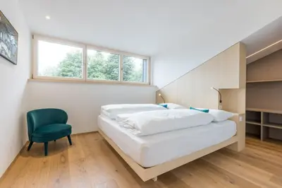 a bedroom with a bed and a green chair at Lisis Loggia in Nova Ponente