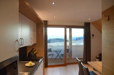 a kitchen with a large window and a table with chairs at Lobishof in Soprabolzano