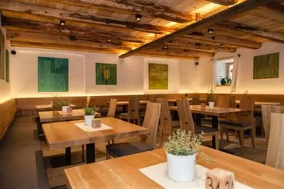 a restaurant with wooden tables and chairs and paintings at Lobishof in Soprabolzano