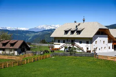 a large white house with mountains in the background at Lobishof in Soprabolzano