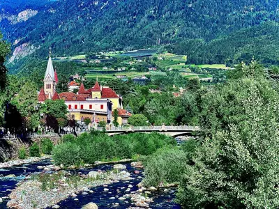 a bridge over a river in a town with a church at Portico ventizerodue in Merano