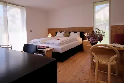 a bedroom with a bed and a table and chairs at Fior Tamion in Vigo di Fassa