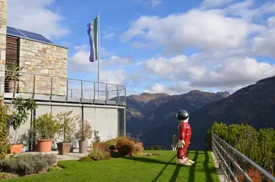 a statue of a person standing in the grass near a building at Fior Tamion in Vigo di Fassa