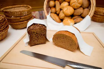 two slices of bread on a cutting board with a knife at Hotel Garni Doris in Castelrotto