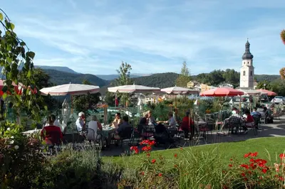 a group of people sitting at tables with umbrellas at Hotel Garni Doris in Castelrotto