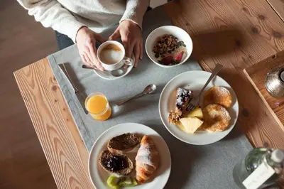 a person sitting at a table with two plates of breakfast foods at Residence Nele in Ziano di Fiemme