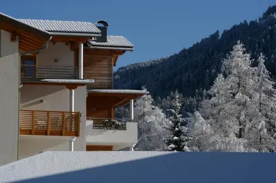 a building with a snow covered mountain in the background at Residence Nele in Ziano di Fiemme