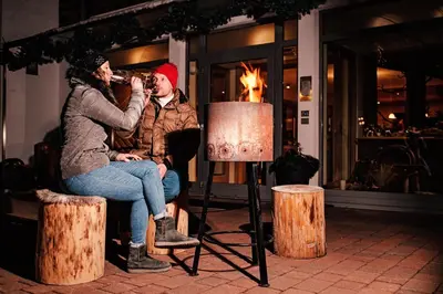 a man and a woman sitting in a chair drinking from a microphone at Residence Nele in Ziano di Fiemme