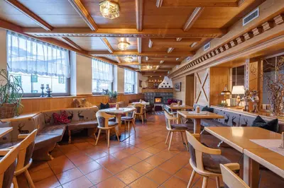 a restaurant with wooden tables and chairs and windows at Hotel Nele in Ziano di Fiemme