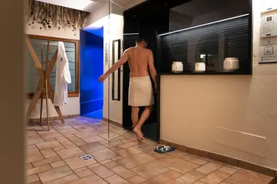 a man in a bathroom looking into a refrigerator at Hotel Nele in Ziano di Fiemme