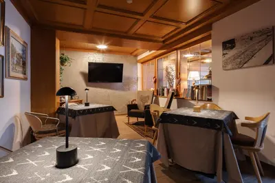 a room with two tables and chairs and a tv at Hotel Nele in Ziano di Fiemme