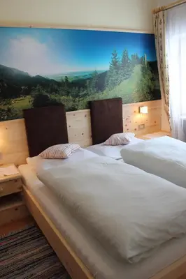 two beds in a room with a large window at Berggasthof Pension Pfitscher in Unsere Liebe Frau im Walde
