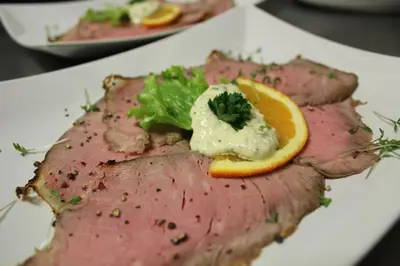 a piece of meat with an orange slice on top at Berggasthof Pension Pfitscher in Unsere Liebe Frau im Walde