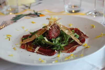 a white plate with a salad on a table at Berggasthof Pension Pfitscher in Unsere Liebe Frau im Walde