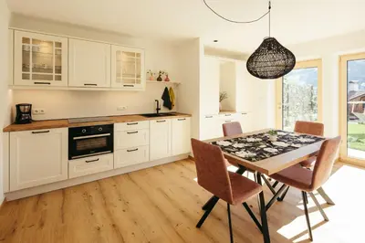 a kitchen with white cabinets and a table with chairs at Villa Bea in Caines