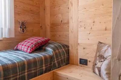 a room with a bed in a wooden room at Cortina Deluxe Chalet R&R in Zuel
