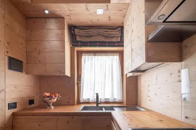 a kitchen in a log cabin with a sink and a window at Cortina Deluxe Chalet R&R in Zuel