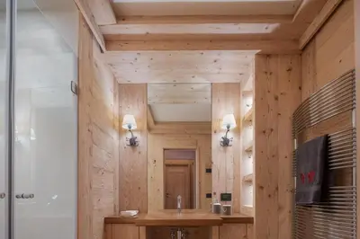a bathroom with wooden walls and a sink and a shower at Cortina Deluxe Chalet R&R in Zuel