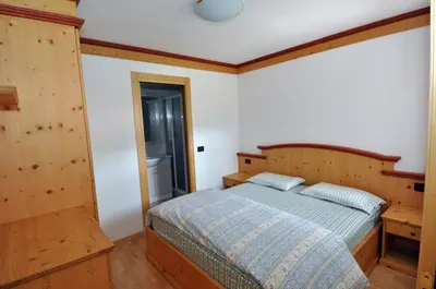 a bedroom with a bed with a wooden headboard at Villetta Giumella in Pozza di Fassa