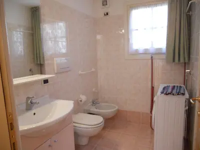 a bathroom with a sink and a toilet and a window at Villetta Giumella in Pozza di Fassa