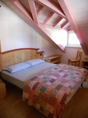 a bedroom with a bed with a quilt on it at Villetta Giumella in Pozza di Fassa