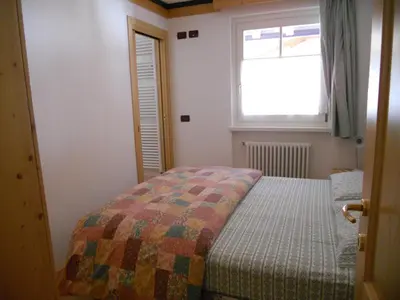 a small bedroom with a bed and a window at Villetta Giumella in Pozza di Fassa