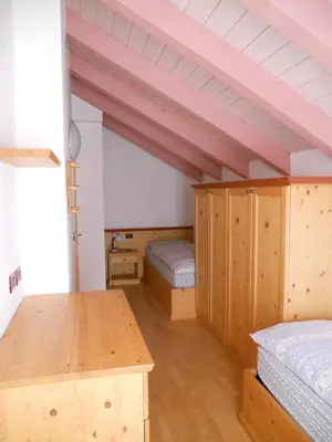 a attic room with two beds and a desk at Villetta Giumella in Pozza di Fassa