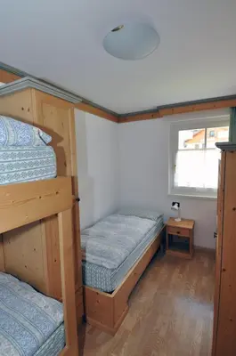 a bedroom with two bunk beds and a window at Villetta Giumella in Pozza di Fassa