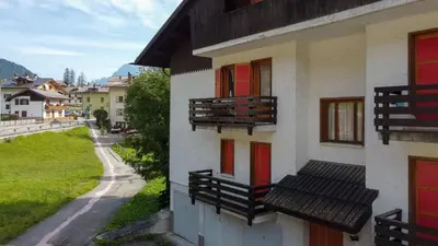 a building with red windows and benches on it at Casa Francesco in Falcade