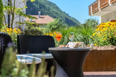 a table with two glasses of wine on a patio at Hotel Garni Grüner Baum (Albero Verde) in Laives