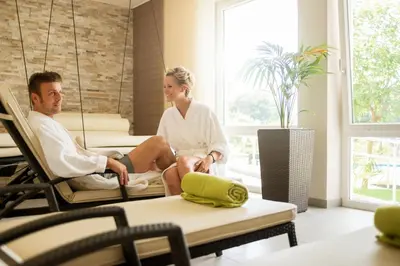 a man and woman sitting on swings in a living room at Hotel Garni Grüner Baum (Albero Verde) in Laives
