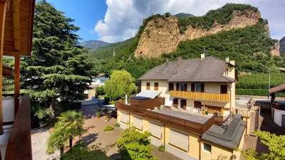 a house with a mountain in the background at Hotel Garni Grüner Baum (Albero Verde) in Laives